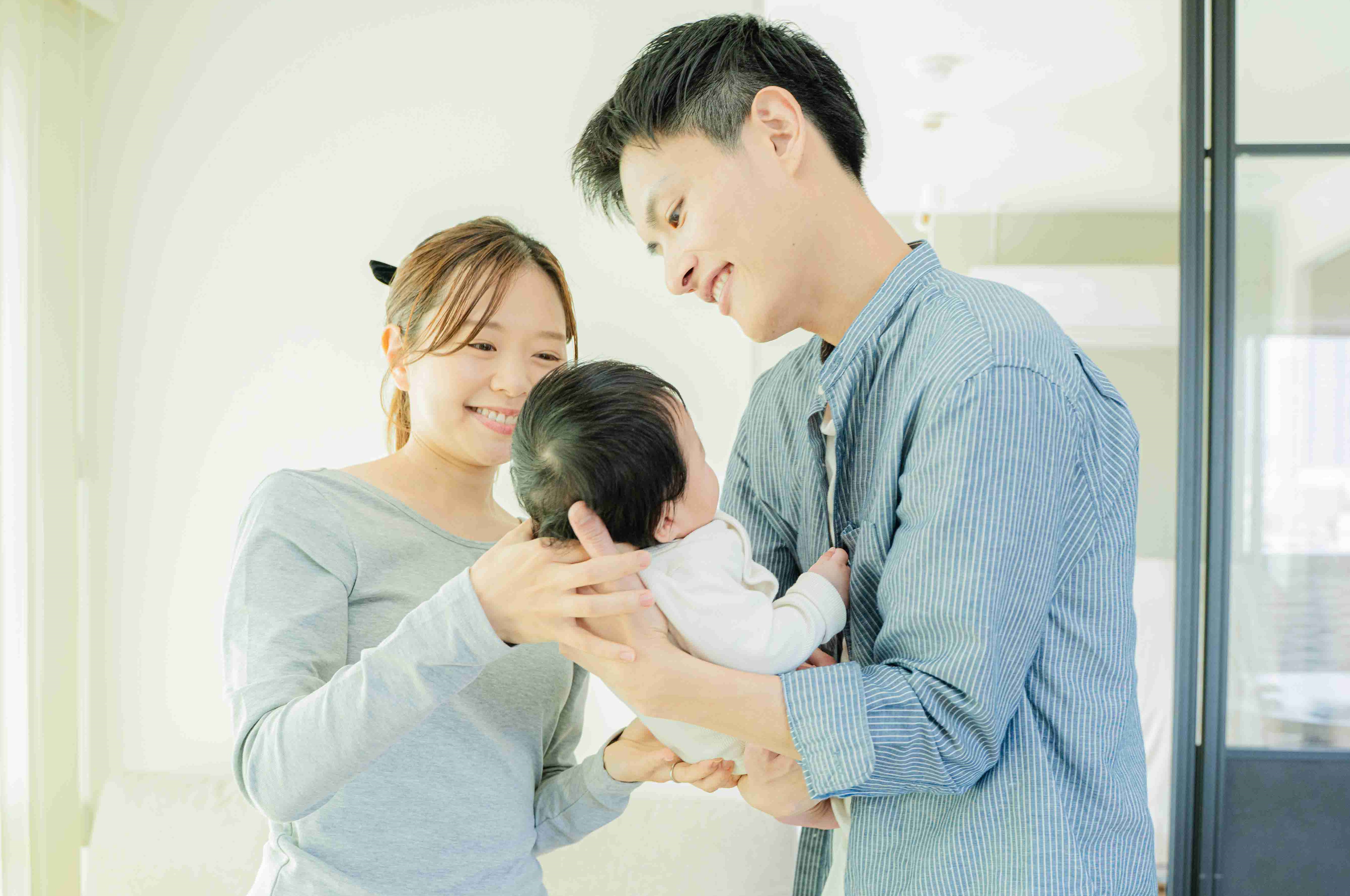 赤ちゃんを大切に抱っこするパパとママ